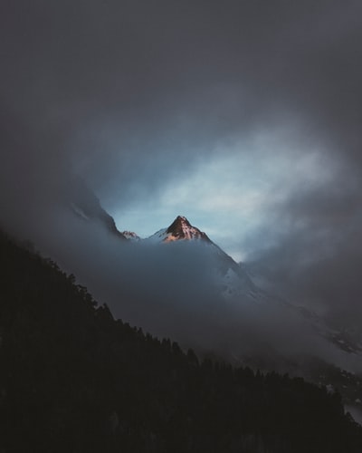 白天多云的天空下，山被雪覆盖